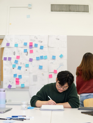 student works taking notes with a plethora of sticky notes all around them
