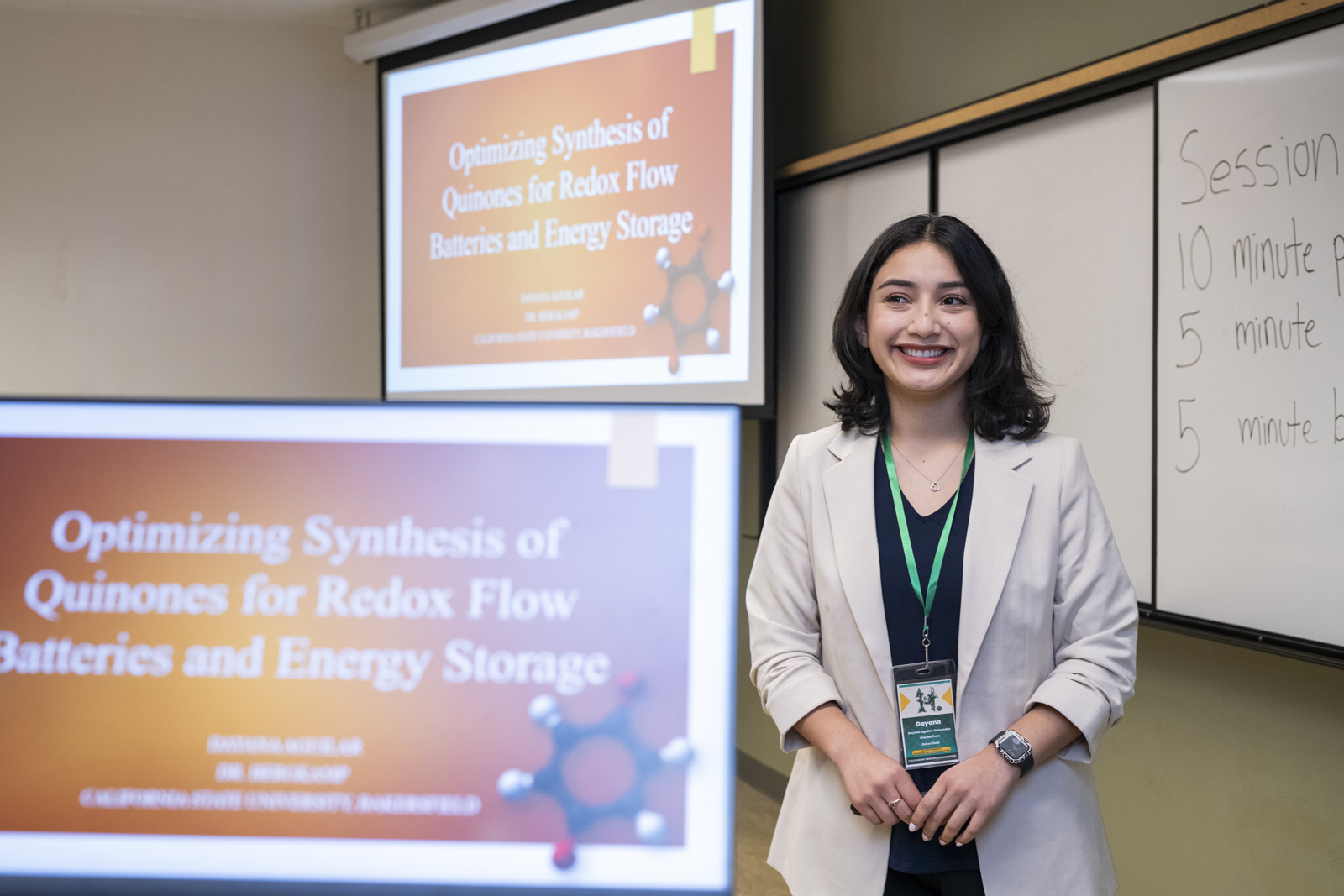 in foreground, computer with presenter loaded. presenter stands behind it, and you can see the projection screen with the presentation in back