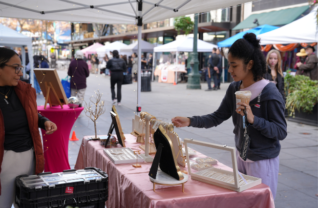 A person shopping from a small business craft vendor in downtown San Jose.